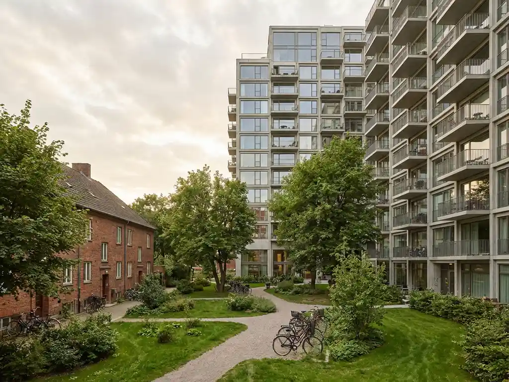 Moderne hoogbouw naast klein bakstenen huis in groene binnenplaats met bomen en fietspaden, Nederlandse sociale woningbouw